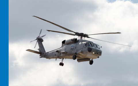 Helicopter in the air with grey clouds behind