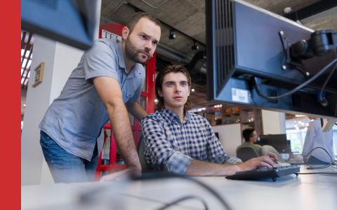 Two male work colleagues looking at computer screen