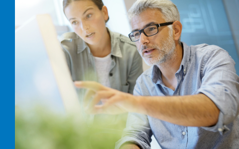 Young woman and man with glasses working together and looking at a computer screen